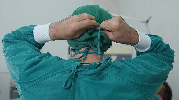 一名男医生在手术室里用一根绳子绑着一个卫生口罩作为手术前的准备