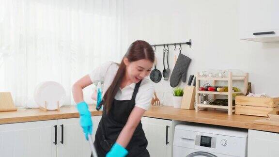 亚洲清洁服务女孩唱歌而清洁厨房在家里美丽的年轻快乐的女人管家清洁工跳舞和拖地工作家务或家务在家里