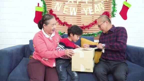 快乐的时刻爷爷和奶奶给孙子一个惊喜的圣诞礼物一起帮忙打开重复使用的纸盒收到恐龙娃娃的男孩非常高兴在庆祝12月的节日装饰了家