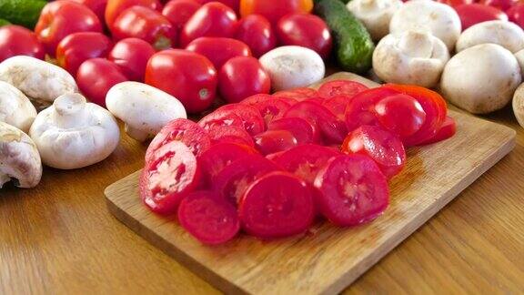 厨房桌子上的木板上的新鲜蔬菜和切西红柿的特写相机旋转