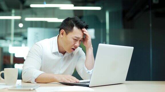 结果不满意的商人在办公室看着笔记本电脑屏幕愤怒的成熟亚洲商人雇员律师分析师经理工人