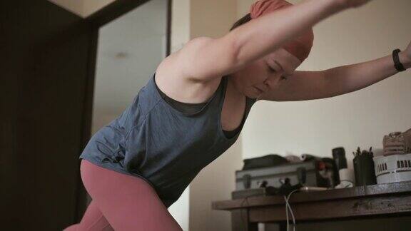 亚洲华人中年妇女头巾练习瑜伽在她的公寓卧室
