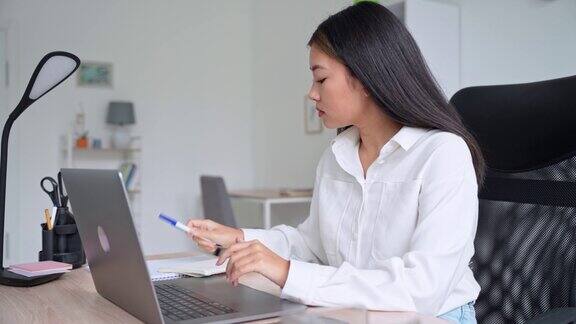 年轻的亚洲妇女在笔记本电脑上工作举行在线会议