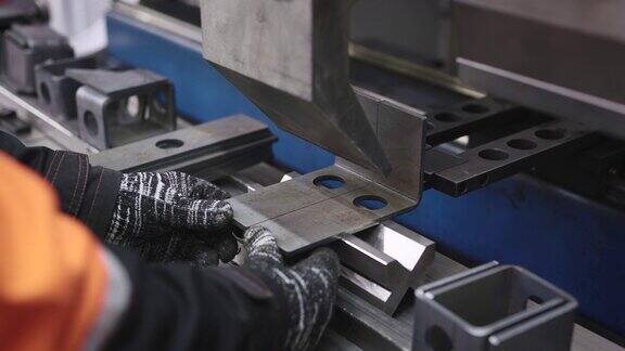 一个特写镜头显示了一个工人的手在一个专门的机器上弯曲钢零件这个车间专门从事金属加工