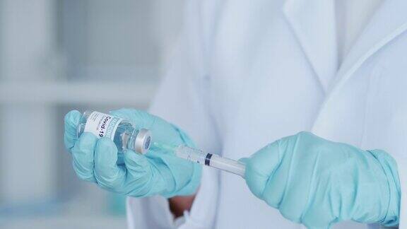 女医生或医师戴蓝色手套和医用口罩手持注射器和小瓶covid-19液体疫苗准备注射免疫和医疗
