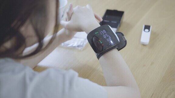 图为一名女子正在家中用数字压力表测量血压和心率
