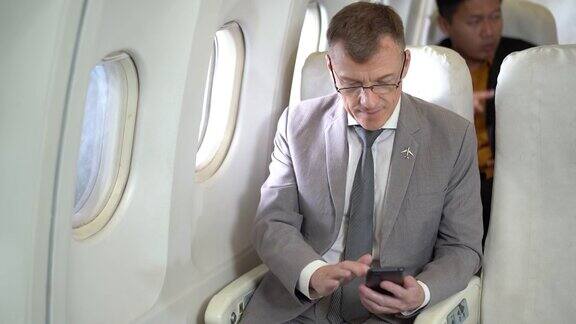 商务乘客坐在飞机上使用智能手机