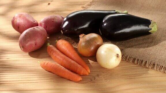 新鲜蔬菜木头背景上的土豆、茄子、胡萝卜和洋葱