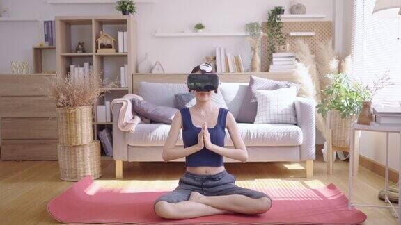 年轻的亚洲女性戴着VR眼镜在家做瑜伽