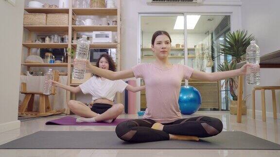 亚洲女子和姐姐用水瓶当哑铃进行重量训练