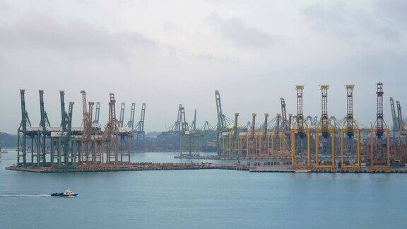 4k新加坡海运港口货船在海上缓慢航行背景是许多集装箱和黄色的起重机