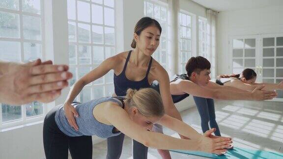 多元化的年轻运动男人和女人学习和训练瑜伽同时由亚洲女教练指导