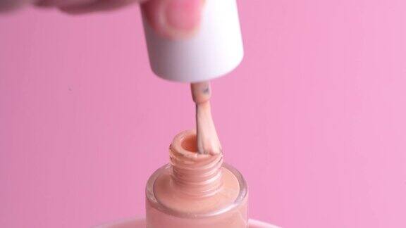 漂亮精致的粉红色指甲油用刷子刷一下罐子的颈部