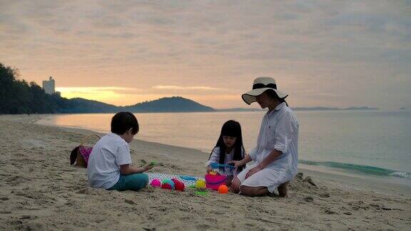亚洲一家人一起在沙滩上玩堆砌的沙子