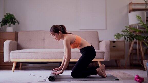 年轻漂亮的亚洲运动女性穿着运动服在家里空旷的地板上摆着瑜伽垫锻炼健康生活方式