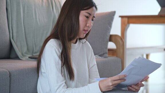 年轻的亚洲女子烦恼债务或错误的每月账单计算费用有财务问题