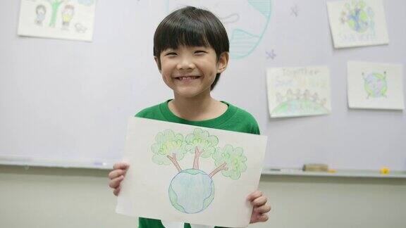 身穿绿色生态t恤的小男孩的肖像手里拿着拯救世界计划的图纸志愿、自然、教育理念