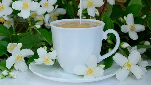 白色杯子里的咖啡把送奶工的牛奶倒进热的美式咖啡里在一杯热卡布奇诺中加入牛奶放在青草和茉莉花上