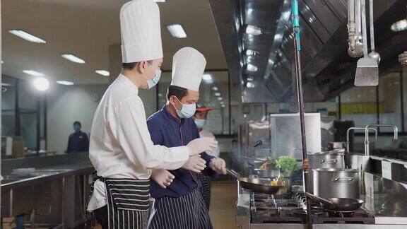 在餐厅的厨房里厨师们戴着防护口罩和手套准备食物