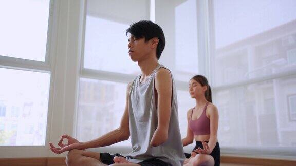 亚洲年轻的没有手臂的截肢者在健身房与教练一起做瑜伽有吸引力的快乐残疾运动员在体育馆里进行运动和锻炼以保持肌肉的健康和健康