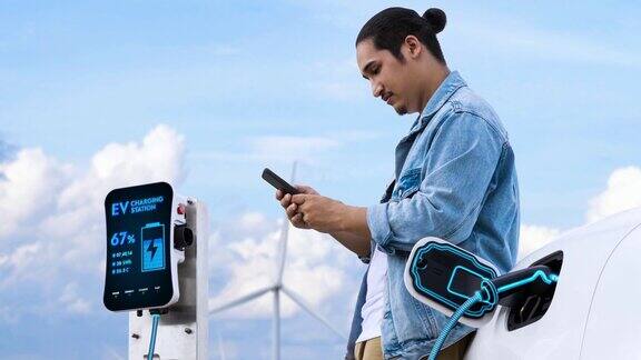 亚洲男子在电动汽车充电时使用智能手机细读