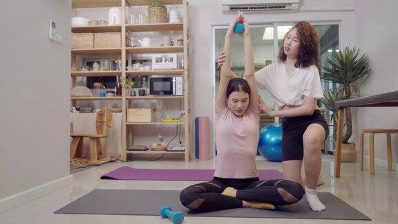 健康的亚洲女子和她的姐姐一起练习哑铃进行在线重量训练