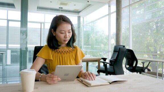 肖像的亚洲女商人工作与数字平板电脑而坐在现代办公室商务人士和技术概念