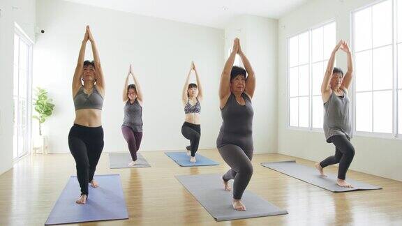 一群亚洲女性几代人在健身房锻炼和练习瑜伽