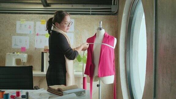 亚洲女性服装设计师为服装设计进行测量和素描