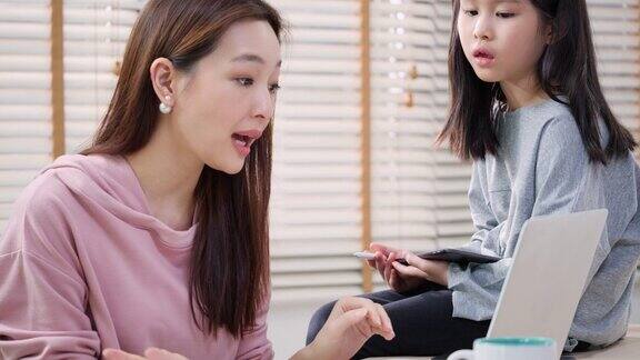 亚洲家庭的商人工作和儿童女孩坐在家里的桌子上母女在家隔离时在网上用会议表达快乐