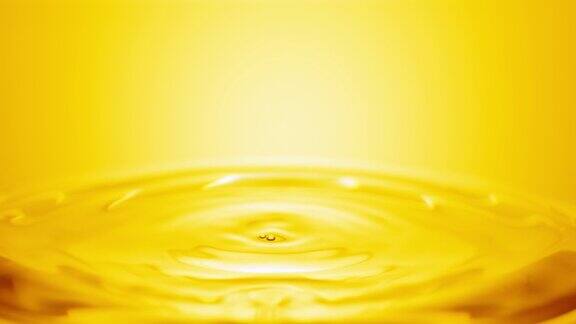 黄色的水滴落在清澈的液体表面形成圆圈