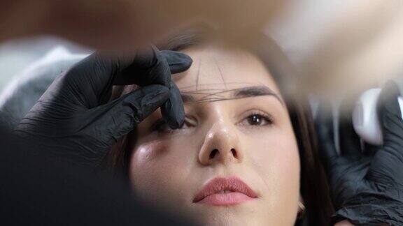美容师正在矫正眉毛的形状美丽的脸一个女孩在美容院