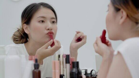 女人坐在镜子前化妆涂口红