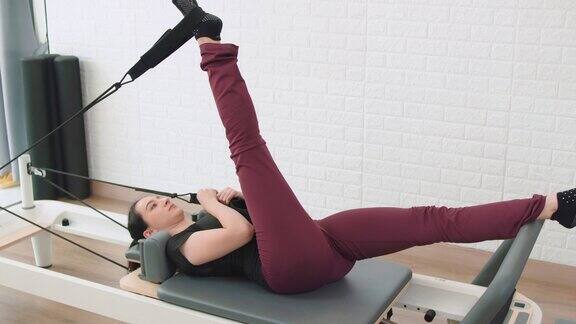 在普拉提健身机上锻炼的女性健康的健身生活方式