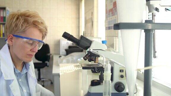 在实验室里使用显微镜的女科学家