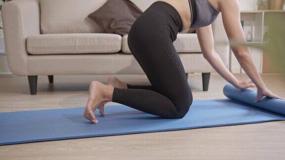 女子铺开瑜伽垫做准备年轻、美丽、健康的运动女性在家里的客厅通过练习瑜伽锻炼身体