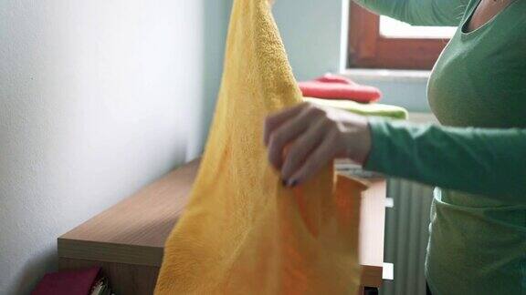 洗衣日-妇女折叠洗过的毛巾