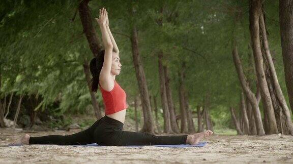 亚洲女人在海滩上的森林里练习瑜伽健康积极的生活方式概念