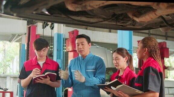 监工正在一家汽车修理厂教机械工人修理汽车
