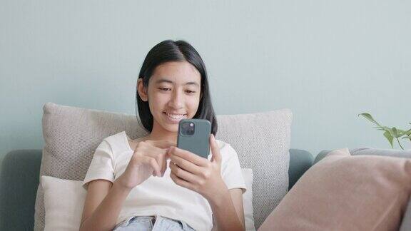 快乐的亚洲女孩用手机发短信或在家聊天