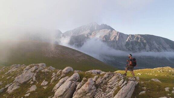 在日落时分一名年轻人在意大利阿布鲁佐山的山脊边缘徒步旅行