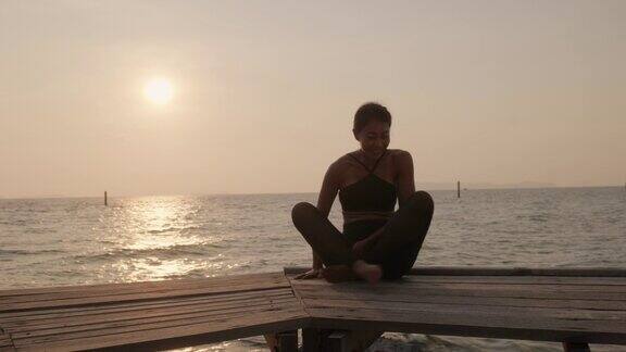 日落时分在海边做瑜伽的女人