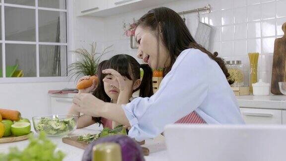 快乐的亚洲家庭近距离拍摄母亲和孩子的女儿正在准备沙拉和切蔬菜在家里的厨房做饭健康食品