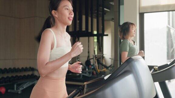 年轻的亚洲运动员在跑步机上跑步在现代化的健身房积极训练