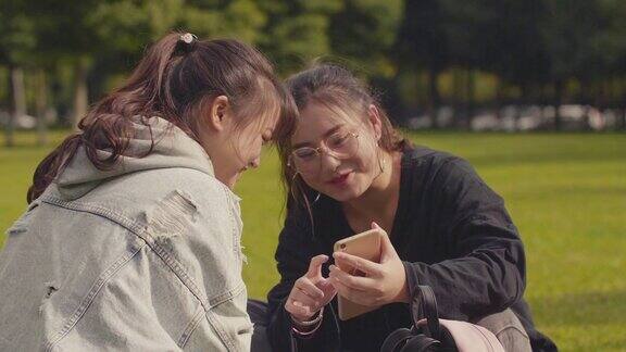 两个亚洲女大学生在校园里使用手机