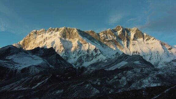 粉色日落时分的Nuptse山和Lhotse南脸尼泊尔的喜马拉雅山脉鸟瞰图无人机横向向上飞行