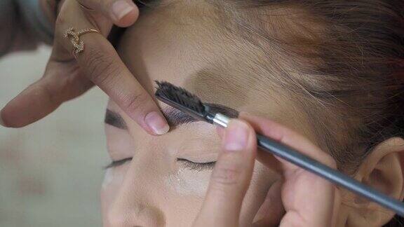 眉妆专业化妆师用特殊的眉刷梳理模特的眉毛特写微距