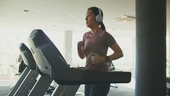 亚洲运动妇女在健身房的跑步机上锻炼