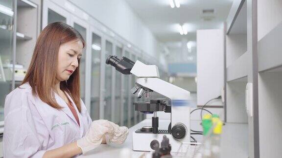 近景女生物学家在现代医学实验室显微镜下检查分析