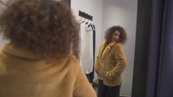 穿着皮草的女人在时装精品店的试衣间里看着镜子